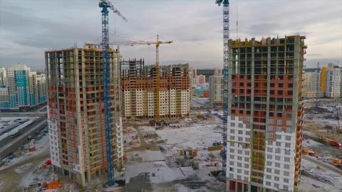 Under construction high-rise building with yellow construction crane in the Stock Photos