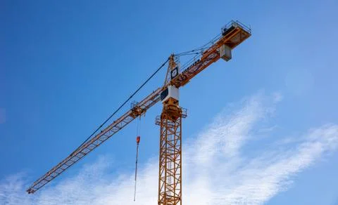 Under construction. Red tower crane on blue sky background Stock Photos