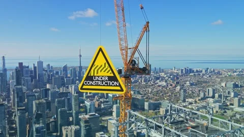 Under construction sign infographic hanging from crane over metropolitan skyline Stock Footage 345491456