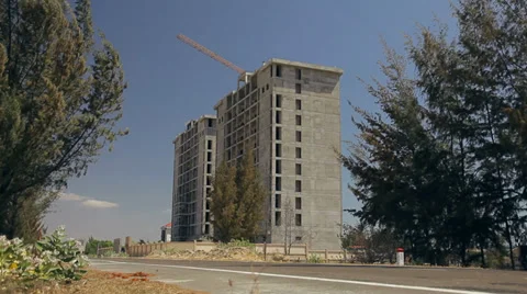 Under construction tall building. Road and trees swaying in the wind. Stock Footage 37811469