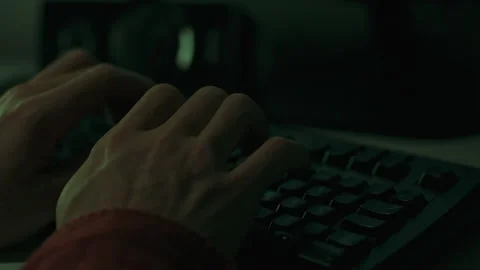 Under dim lighting man is busy working at his desk with a laptop computer. H Stock Footage 256935718
