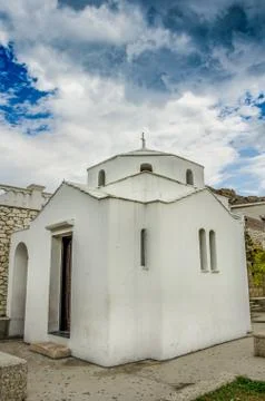 Under a dramatic sky a small white chapel in central square of town Skyros. S Stock Photos