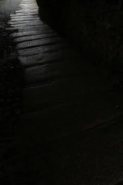 Under exposed image of a granite footpath through a tunnel. Stock Photos