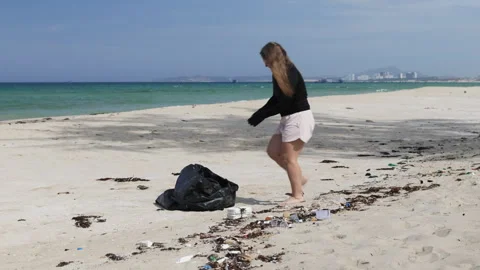 Under an open sky, a lone figure bends to clean the abandoned sands. Stock Footage 310992601