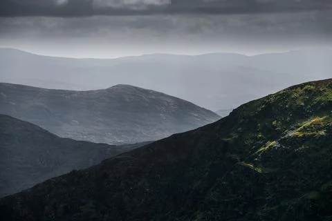 Under a soft cloudy sky, lush green mountains Stock Photos