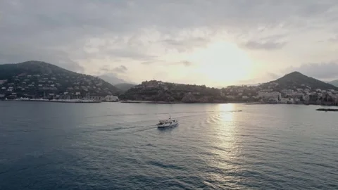 Under a soft sunset glow, a lone boat glides through the tranquil waters off Stock Footage 316213241