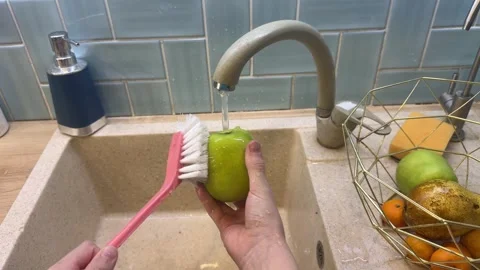 Under sunny kitchen light, a vegan child rinses just-picked apples with care Stockbeeldmateriaal 331569807