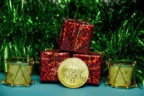 Under the tree, among the gift boxes, lies a gold bitcoin coin. Cryptocurrency Stock Photos