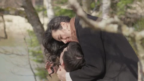 Under the trees, the couple gives each other kisses, feeling the magic of the Stock Footage 263654594
