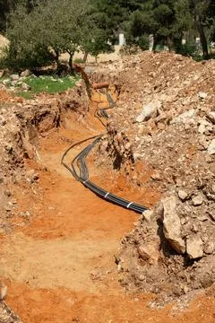 Underground Cable Installation in Trench. deep trench cut through rocky ora.. Stock Photos