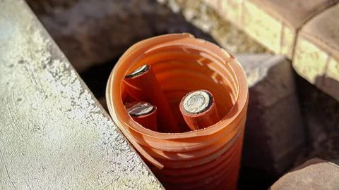 Underground cables in orange conduit pipe during installation Stock Photos