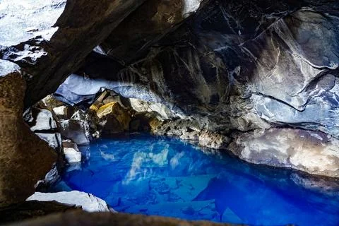 Underground cave with hot clear blue water in Iceland, long exposure in dar.. Stock Photos