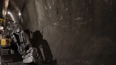Underground construction zone powerful hydraulic breaker drills into tunnel wall Stock Footage 309664192