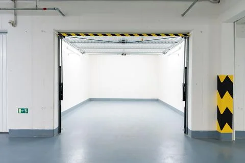 Underground empty garage with open door and bright lighting in modern apartment Stock Photos