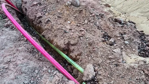 Underground fiber optic cable installation in a trench at a construction site Stock Footage 337791280