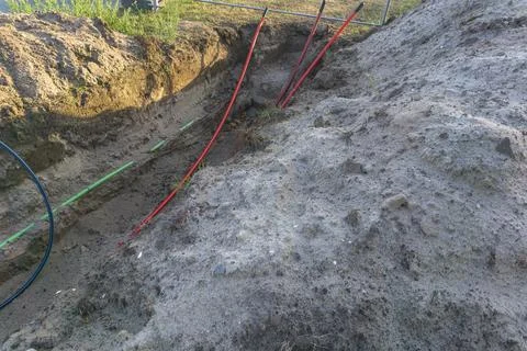 Underground infrastructure installation showing red utility pipes in dirt Foto stock