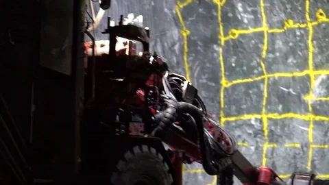 Underground jumbo driver drilling into rock and charging face of wall in Stock Footage 121589029