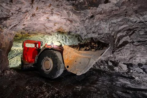 An underground loading machine carries a full bucket of ore. Special low-profile Stock Photos