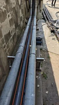 Underground power cable routing through black HDPE conduit pipe with orange. Stock Photos