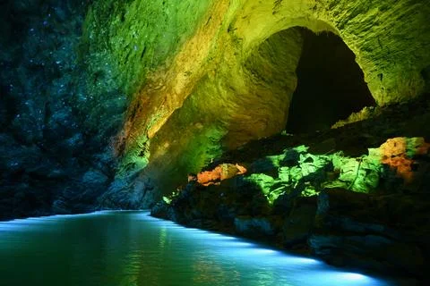 Underground river illuminated by colored light in Yellow Dragon Cave in China Stock Photos