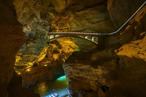 Underground river, pier and bridge illuminated by light in Yellow Dragon Cave Stock Photos