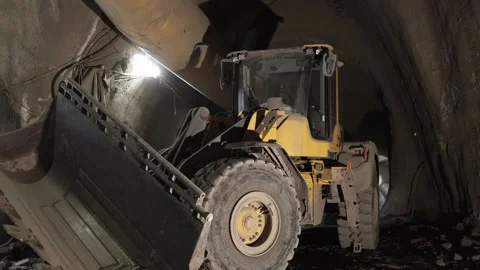 Underground tunnel construction dirty yellow loader stands under curved concrete Stock Footage 309667716