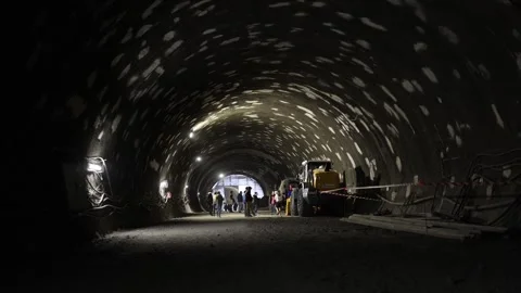 Underground tunnel construction scene with workers in helmets walking under patc Stock Footage 309660718