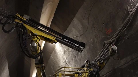 Underground tunnel drilling robotic arms extend toward concrete wall heavy cable Stock Footage 309664451