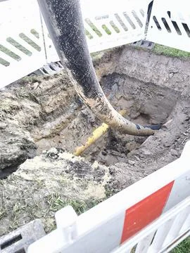 Underground utility repairs. A pit with pipes and dirt, enclosed with plastic Stock Photos