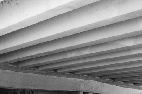 Underneath a concrete bridge, parallel beams form a bold industrial pattern Stock Photos