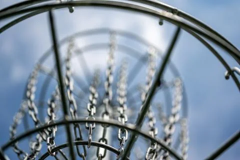 Underneath a disc golf goal looking up with selective focus on the chain basket. 写真素材