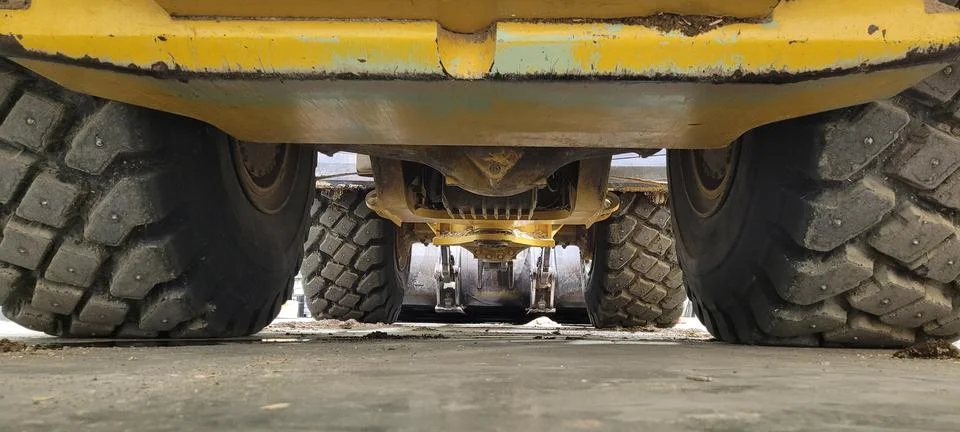 Underneath Heavy Loader Chassis with Large Studded Tires and Yellow Paint 스톡 사진