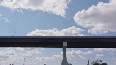 Underneath highway road way with car traffic summer day with white cloudscape Stock Footage 343436554