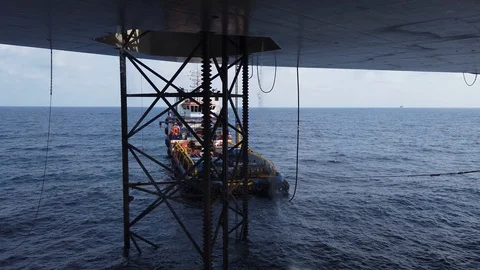 Underneath a jack up drilling rig and supply boat Stock Footage 123748715