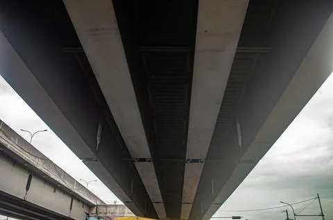 Underside of an elevated highway structure showing concrete beams and cloud.. Stock Photos