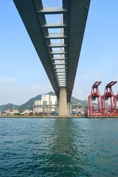 Underside of a Large Bridge with Port Cranes and Coastal Background Stock Photos