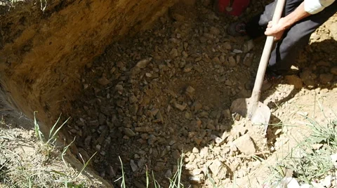 Undertaker digging a hole with a shovel for a grave