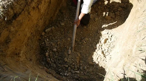 Undertaker digging a hole with a shovel for a grave