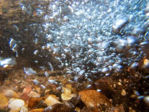 Underwater abstract image of a bubbles in stream with colorful stones Stock Photos