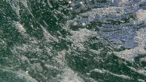 Underwater air bubbles and tiny particles drift through seawater with reflected Stock Footage 339279407