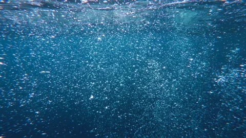 Underwater air bubbles rising to surface through deep blue water 스톡 동영상 327947347