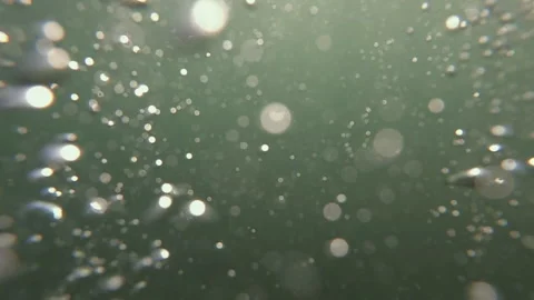 Underwater air bubbles slowly rising against a green background, light creating Stock Footage 343076857