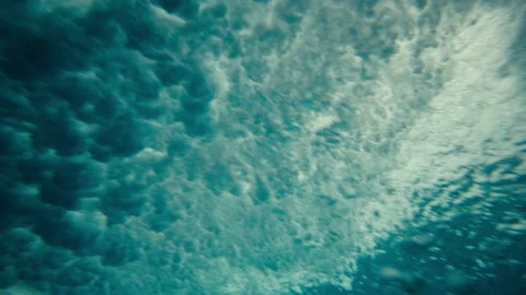 Underwater beneath large wave whitewash crashing bubbles mist blue surface Stock Footage 333149157