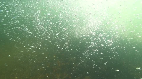 Underwater bubbles drift illuminated by sunlight in slow motion Stock Footage