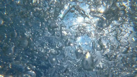 Underwater bubbles rising toward sunlit surface in ocean water Stock Footage 342156748