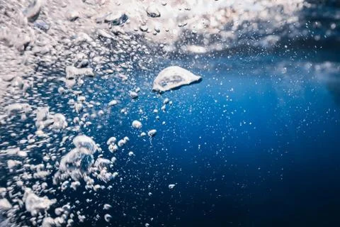 Underwater bubbles texture in blue ocean. Air bubbles in sea with sun light. Photos