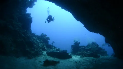 Underwater cave entrance, with a scuba diver and shark silhouette Stock Footage