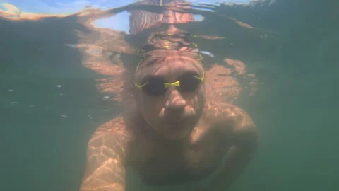 Underwater close-up of a man's face while snorkeling with yellow goggles in the Stock Footage 344830027