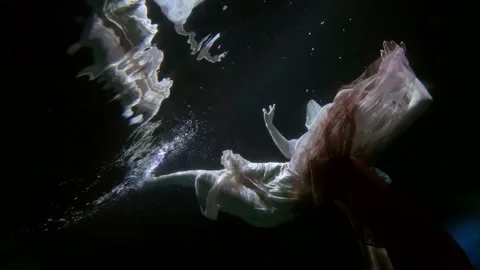 Underwater dive inside dark water of lake or pool, graceful mysterious woman is 스톡 동영상 167279651