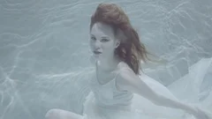 Beautiful Red Haired Woman In A White Dress Swimming Under Water